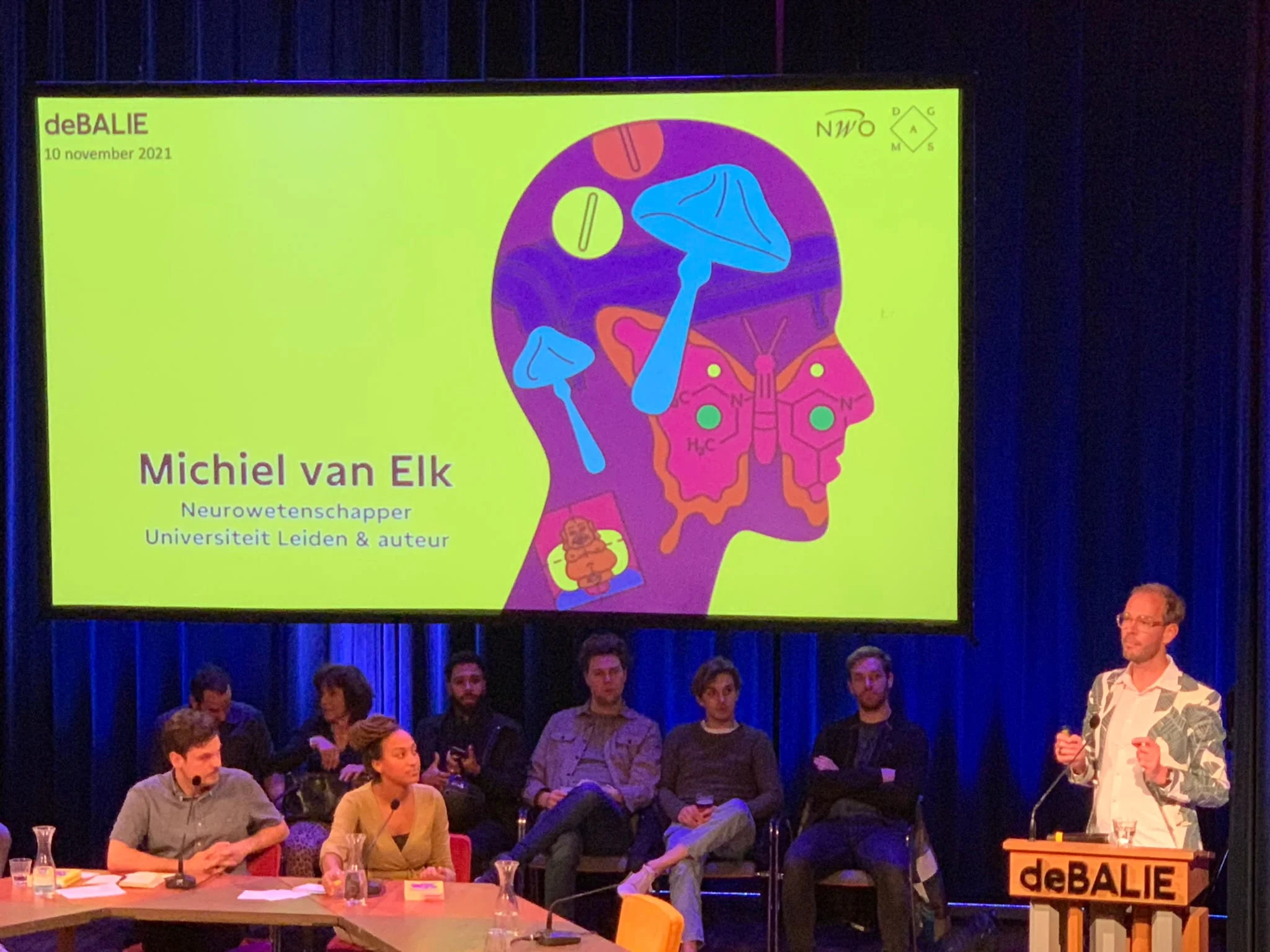 Michiel van Elk speaking on stage at a deBalie event about psychedelics